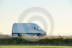 Small cargo van driving on highway hauling goods. Delivery transportation and logistics concept