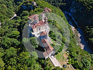 a small castle with many red roofs and two chimneys with stone walls: Georgia, Motsameta Monastery