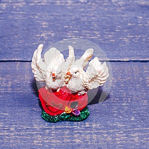 Small ceramic doves on hearts on a wooden background. Souvenir, gift