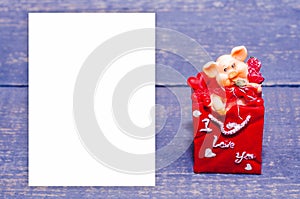 A small ceramic pig in a red envelope on a wooden background. Souvenir, gift