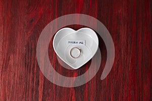 Small ceramic saucer in the shape of a heart with a ring and a note