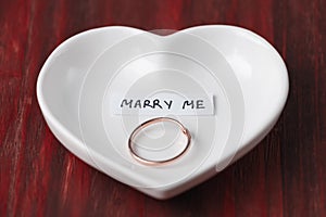 Small ceramic saucer in the shape of a heart with a ring and a note