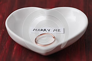 Small ceramic saucer in the shape of a heart with a ring and a note