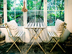 Small chairs and table with garden view through window