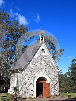 Small old chapel with open door by blue sky