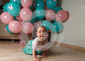 A small, charming child, a girl, celebrates her first birthday, sitting next to her with balloons. Children`s Party Organization.