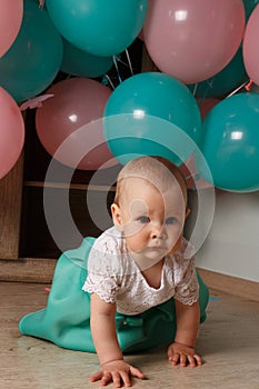 A small, charming child, a girl, celebrates her first birthday, sitting next to her with balloons. Children`s Party Organization.