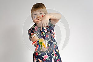 A small cheerful smiling girl shows index finger at leftist hands that she got dirty in facial paint photo