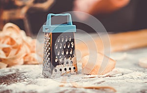 Small cheese grater and piece of cheese closeup on the cusine table. photo