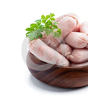Small chicken sausages in wooden bowl isolated on white