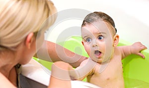 Small child bathes in a bath with his mother.