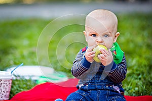 A small child bites a large green apple .