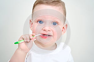 a small child with blue eyes holds toothbrushes in his hands.