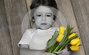 A small child with a bouquet of yellow tulips. A boy with a gift