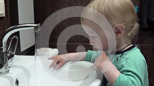 A small child, a boy, brushes his teeth on his own, early in the morning in the bathroom.