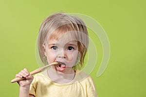 A small child brushes his teeth with an eco-friendly brush on a green background