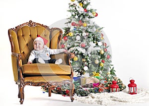 Small child in a cap Claus's sonata sits in chairs about a Christmas tree