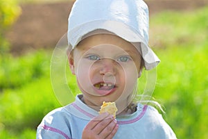 Small child in a cap eating cookies