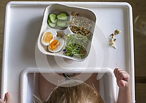 A small child at the children`s table is going to eat healthy food from sprouted grains and eggs. Vegetarian food