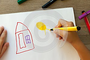 A small child draws a house with markers in the album. Step-by-step instructions photo