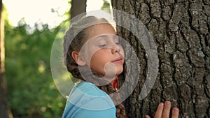 a small child ecologist hugs the trunk of a tree bark in a forest park. the gentle touch of a child on the trunk of the