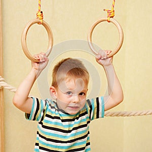 Small child exercising on gymnastic rings