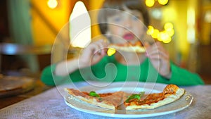 A small child in a fast food cafe eats pizza. Portrait of cute funny little caucasian kid boy eating delicious Italian