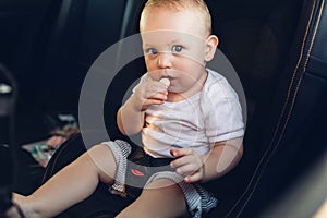 Small child is fastened with a seat belt on the car safety seat
