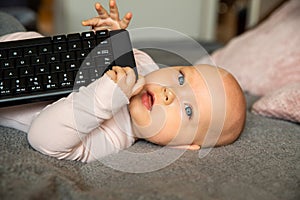 Small child, first steps on the internet, a newborn baby is holding a keyboard from the computer