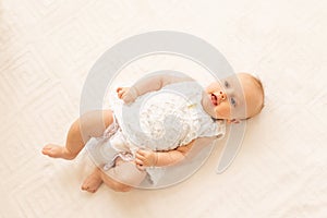 A small child a girl 6 months old is lying on a white bed