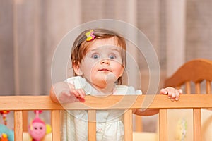 Small child with a hairpin standing in crib.