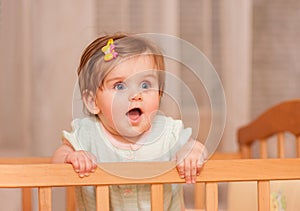 Small child with a hairpin standing in crib.