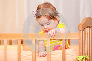 Small child with a hairpin standing in crib.