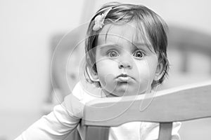 Small child with a hairpin standing in crib.