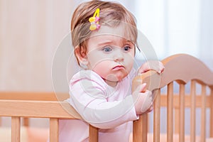 Small child with a hairpin standing in crib.