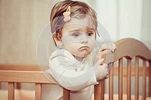 Small child with a hairpin standing in crib.