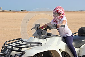 Small child in head kerchief on quadbike