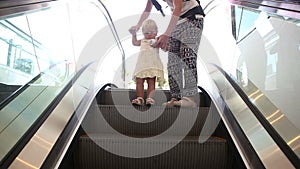 Small Child and her Mother Move on Escalator