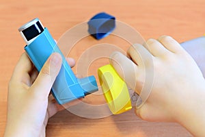 Small child holding asthma inhaler and spacer in his hands. Asthma spacer and aerosol inhaler photo