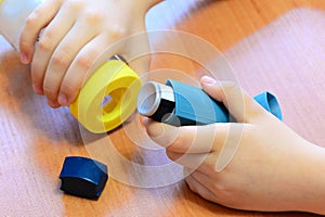 Small child holding asthma inhaler and spacer in his hands. Medication and medical devices