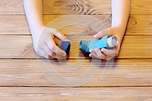 Small child holds asthma inhaler in his hands. Inhalation treatment of respiratory diseases. Allergy and bronchial asthma concept photo