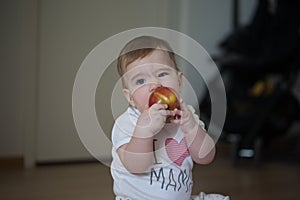 Small child holds his hands apple and gnaws