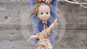 Small child holds an old broken doll by the hand and by the hair