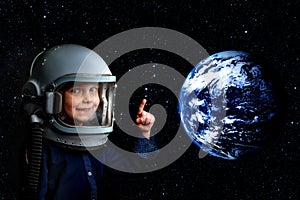 A small child imagines himself to be an astronaut in an astronaut`s helmet.