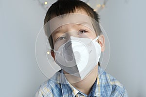 Small child, kid 7-8 years old in a white mask class FFP2, close-up face, medical concept, tired of quarantine, concept of COVID-