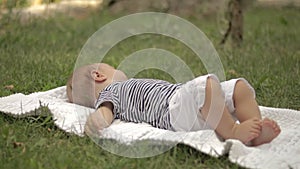 A small child lies on the grass grins and plays