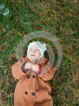 A small child lies on the ground and smiles. Top view. The concept of autumn leaves for children. A smile on a child