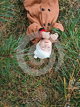 A small child lies on the ground and smiles. Top view. The concept of autumn leaves for children. A smile on a child