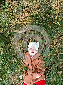 A small child lies on the ground and smiles. Top view. The concept of autumn leaves for children. A smile on a child