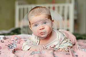 Small child lies on his stomach, drooling with bubbles on  lips, girl holds her head with difficulty